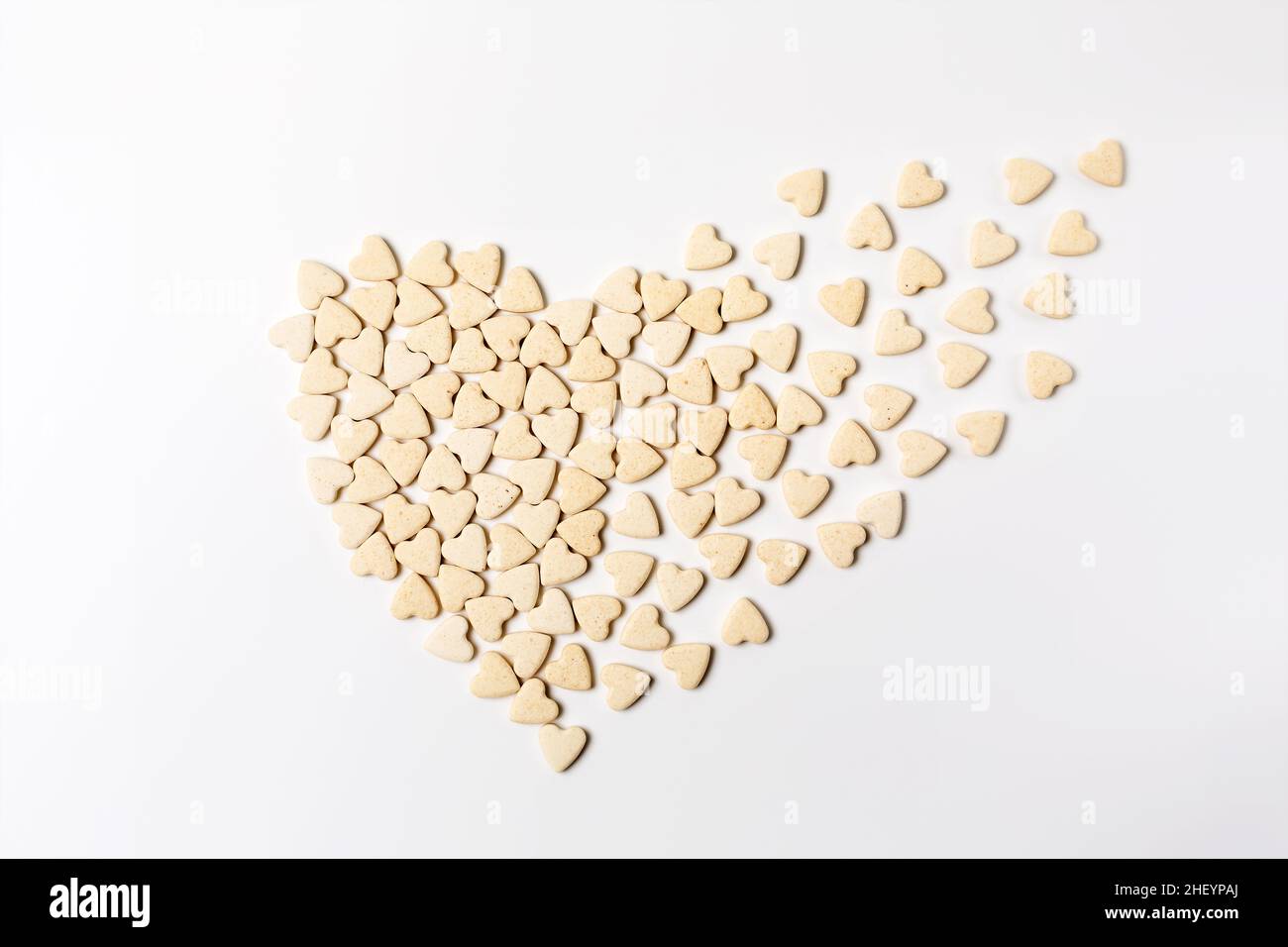 Heart-shaped little sweet cookies in form of dissolving heart on white background, minimalistic saint valentine`s day greeting card Stock Photo